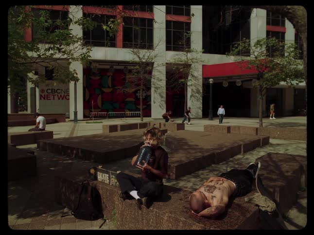 Boy sitting drinking water and his friend next to him who is lying down asking for water