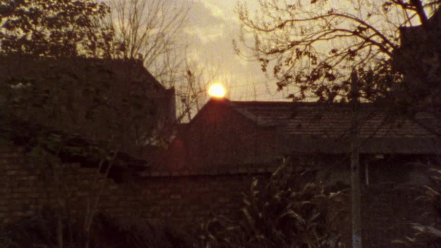 The sun sets over the rooftops of a urban landscape
