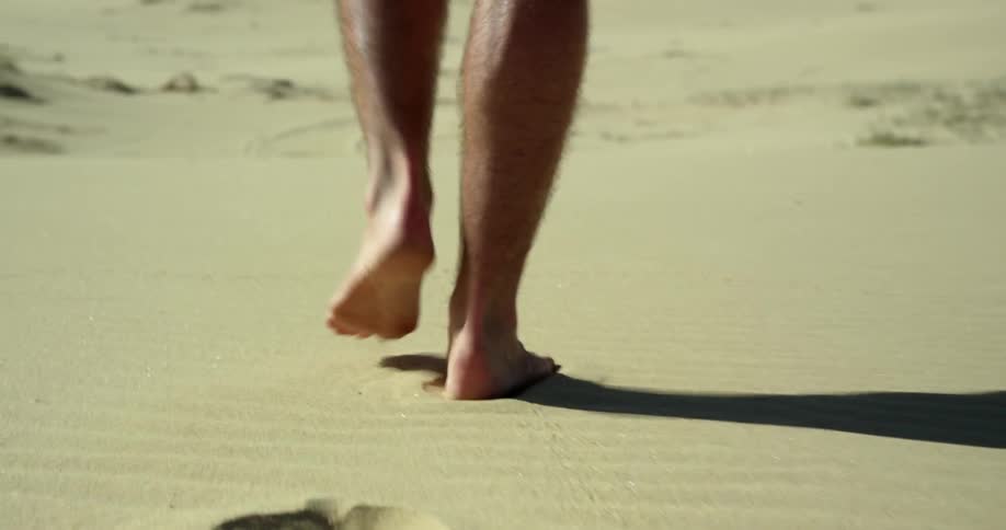 A person walking on sand across a desert