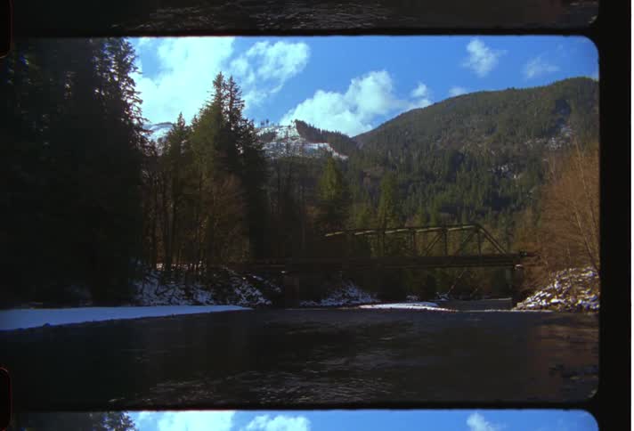 An image of an over head bridge above a river close to a mountainous area