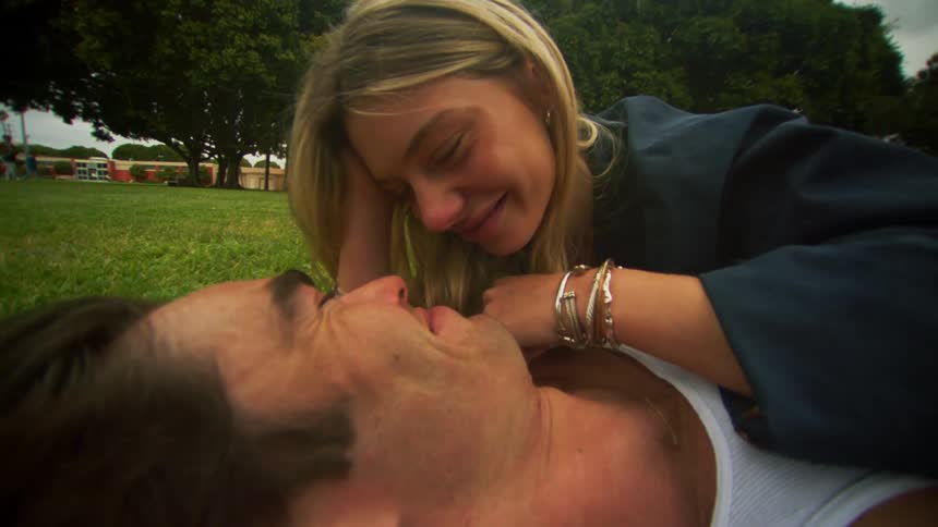 Man and woman lying in a park on the grass and kissing romantically