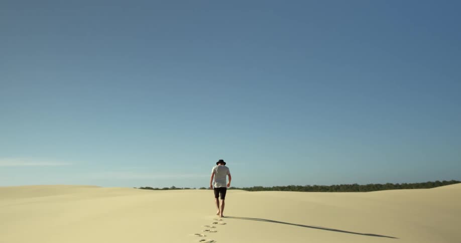 Man walking across sand on windy day