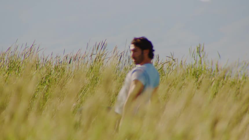 A man dances in the tall grass a smile gracing his face