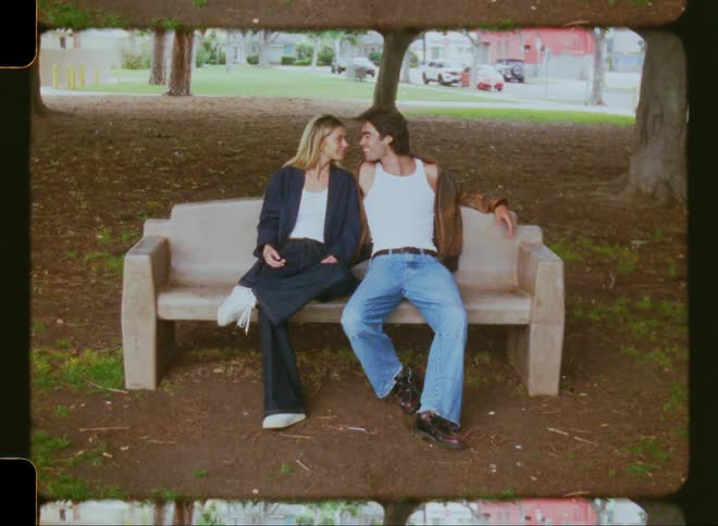 Couple sitting on a cement chair in a park kissing