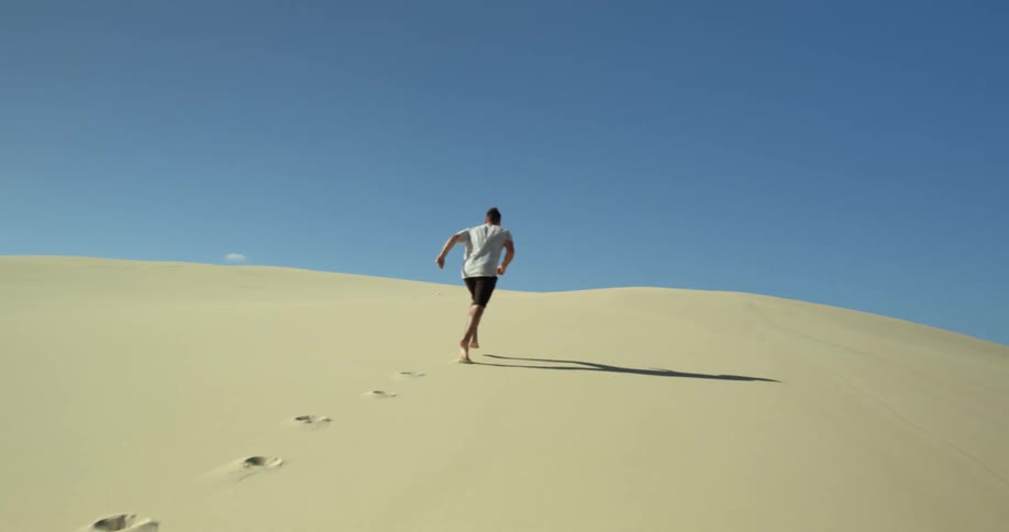 A man running across the sand of a desert