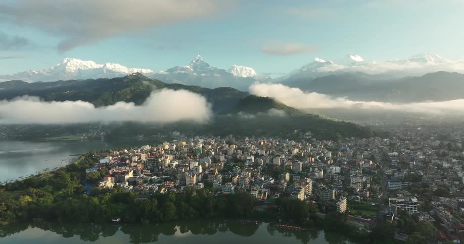 City borders reflective water and multiple mountains under a cloudy sky
