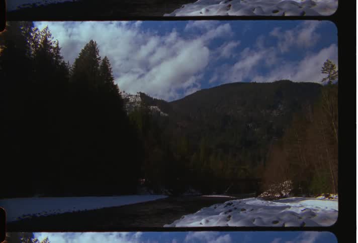 Landscape with a river and snowy bank with mountains in the background