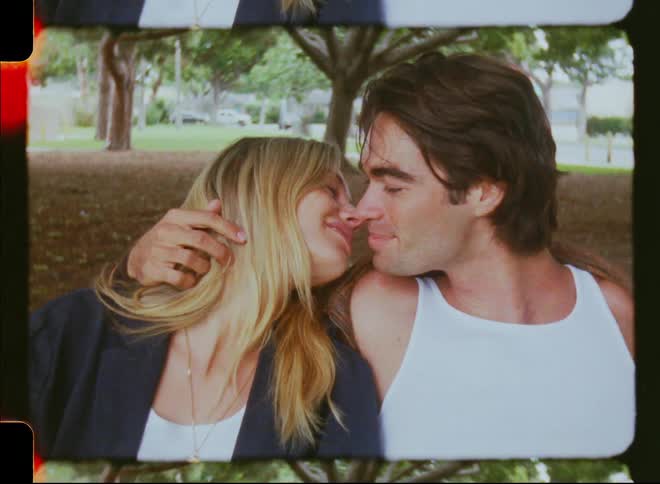 A couple kisses in a public park during summertime
