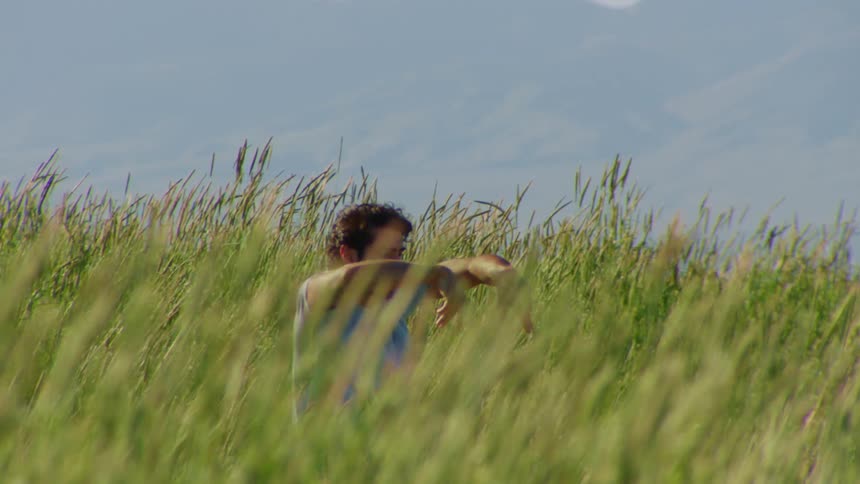 A man dancing in a field of tall grass
