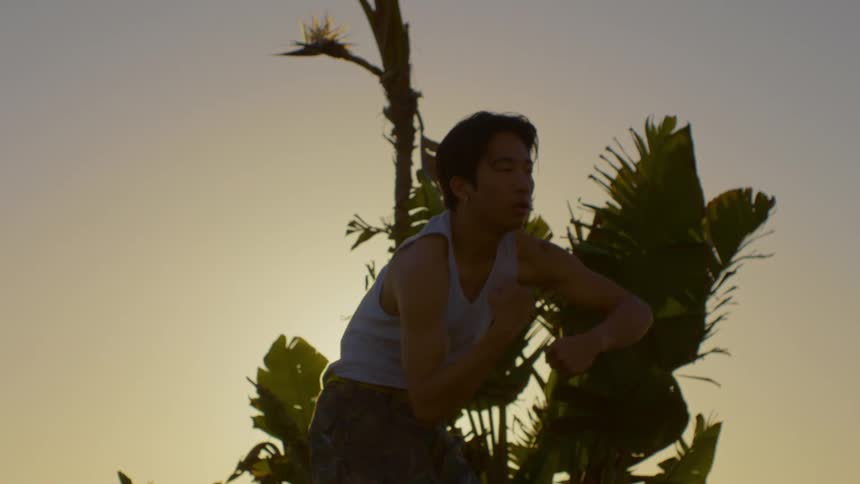 Man in tank top moving his arms and dancing against the sunset
