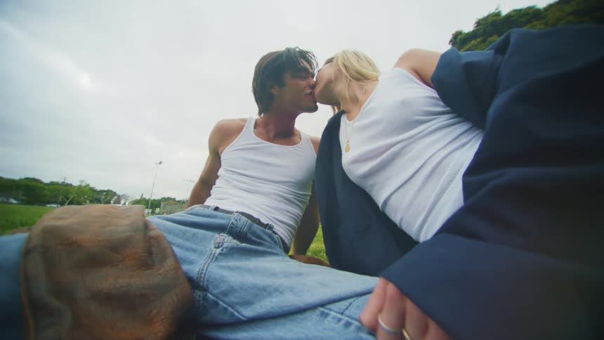 Couple sitting on the grass in the open and kissing