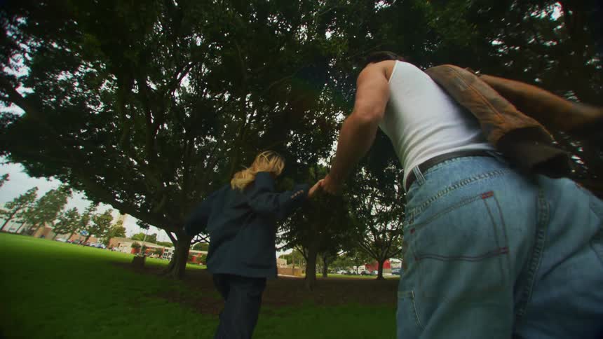 A couple run in the park while holding hands