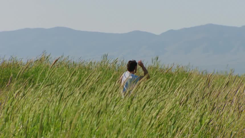 A man dancing in a field of tall grass