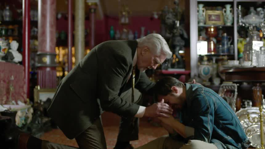 A man consoles another man who starts crying in antique shop