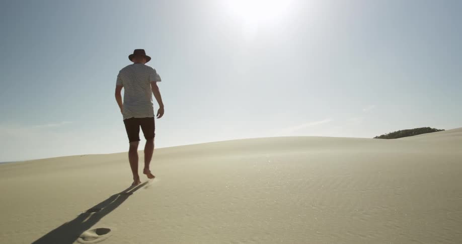 A man walks up a sand hill