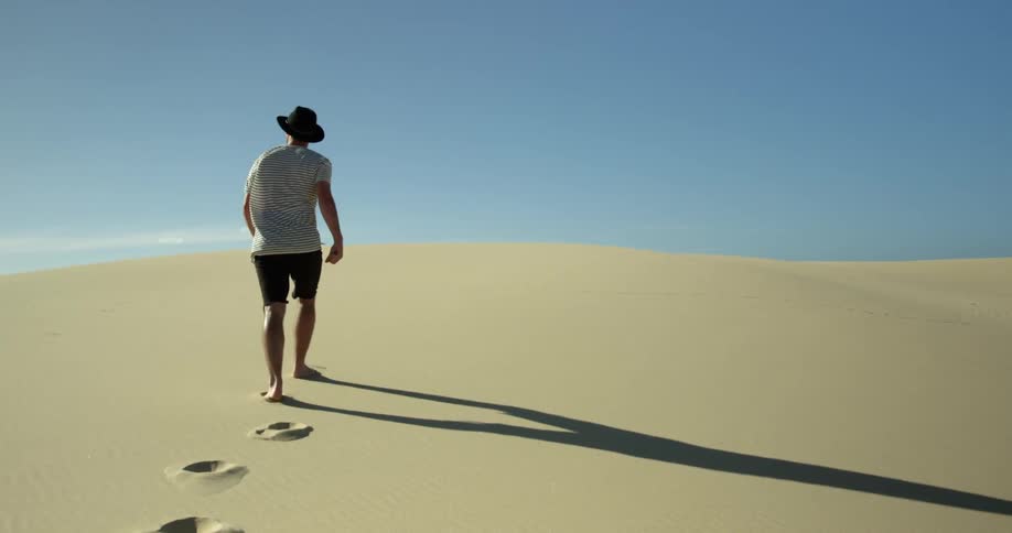 A man walks up a sand hill
