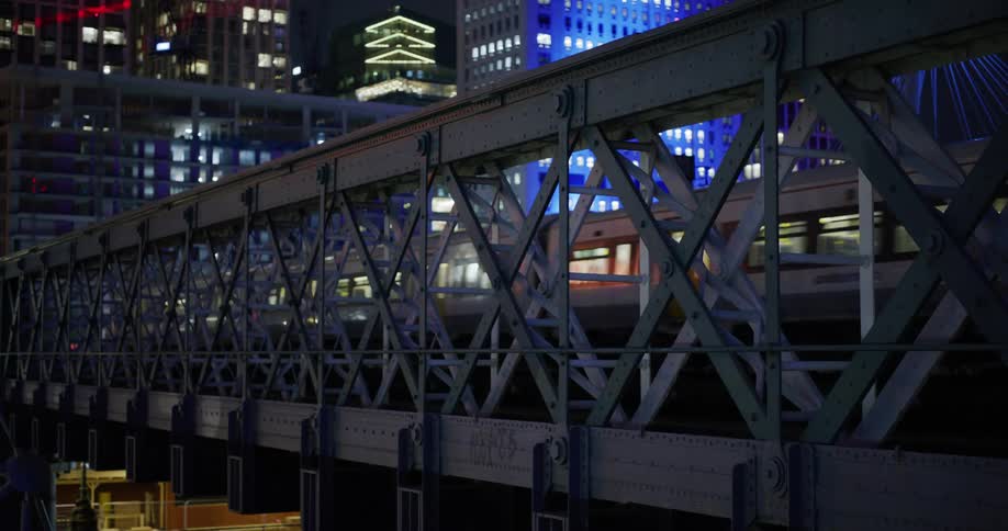 A train in a city crossing a metallic bridge