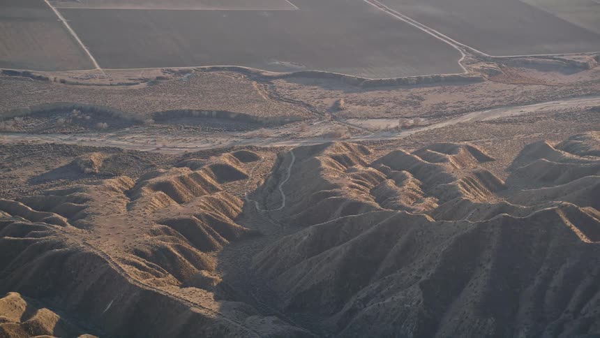 Aerial view of a distant agricultural field next to rocky mountains