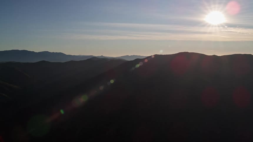Landscape of a strong sun reflecting on the silhouettes of mountains