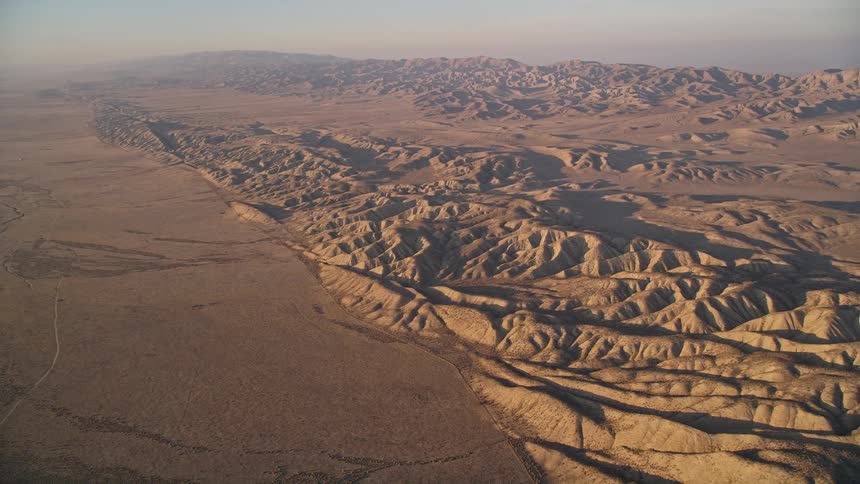 Aerial panorama of hills and mountains in a desert environment against a morning sky