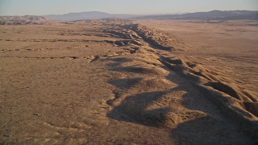 A desert with a line of dunes and mountains in the background