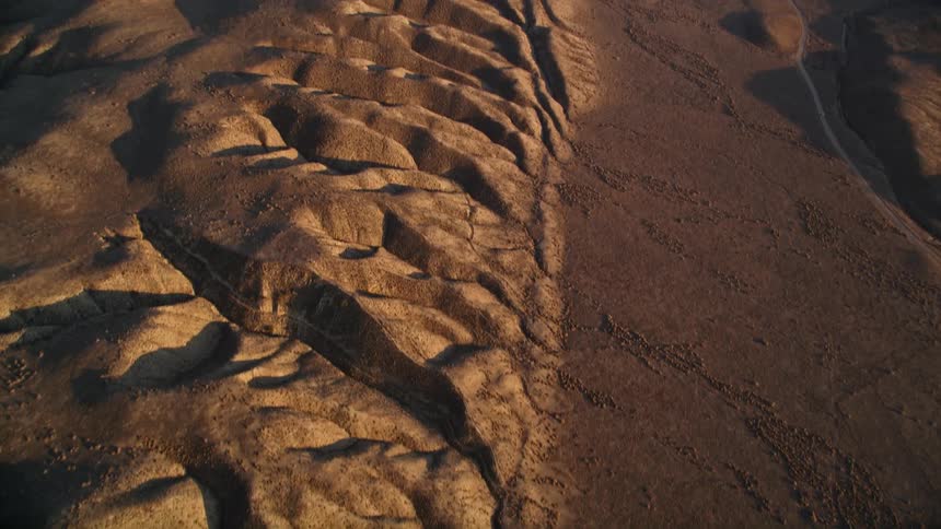 Aerial aerial panorama of a desert floor with fissures in a mountain valley