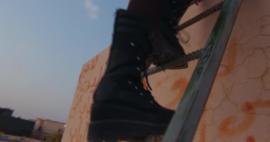 Closeup of black leather boots worn by a person climbing a ladder