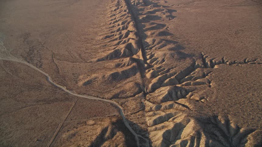 A mountain range with a road running through it in a desert