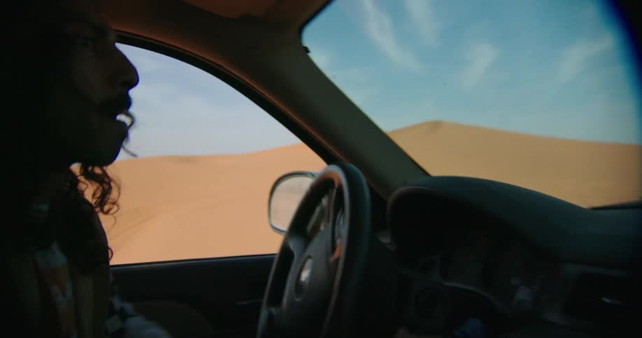 Young man driving through desert dunes