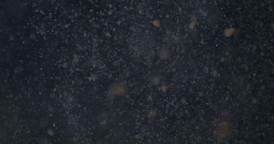 Dense powder falling through a liquid against a dark background