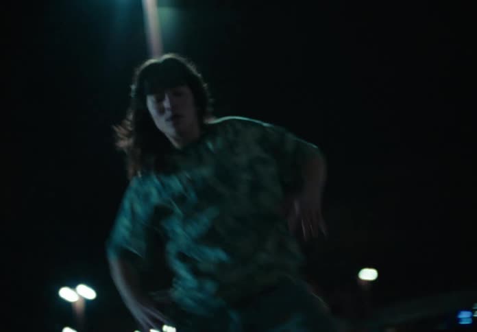 Woman dancing in an outdoor environment with streetlights lit at night around her