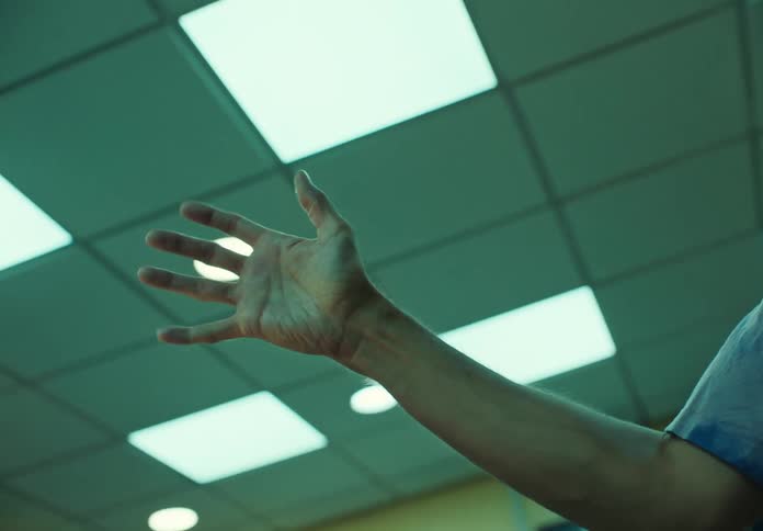 A man lifts his arm and bends his fingers