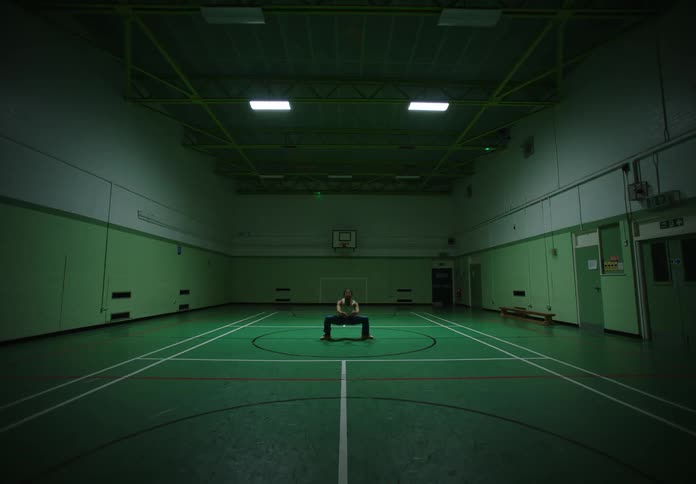 Man dances in the middle of an interior basketball court