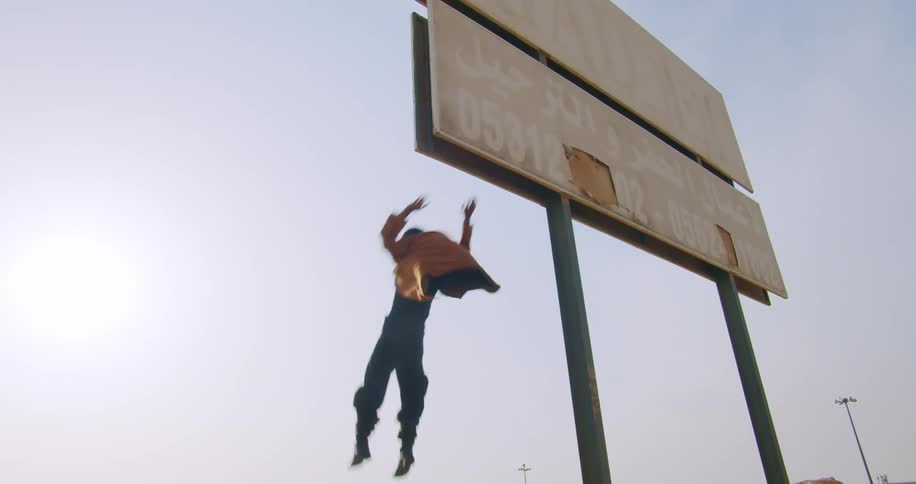 Man wearing a yellow jacket and black pants hanging off a billboard