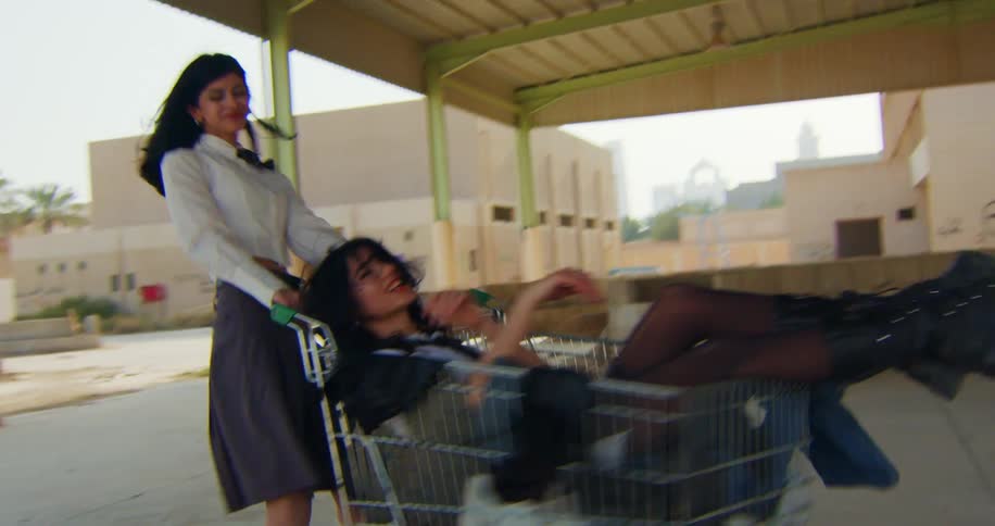 A girl has fun spinning her friend around in a grocery cart