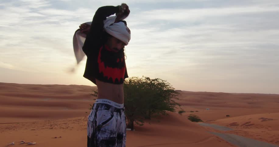 A man covers his head in the desert