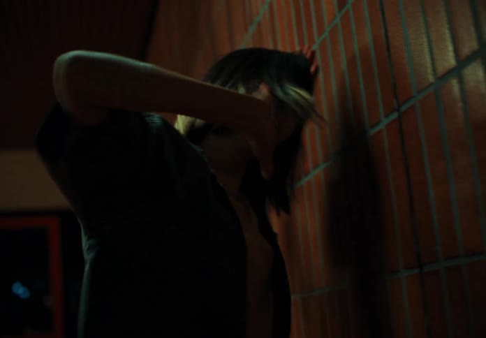 A woman is hitting a red tile wall using her hand