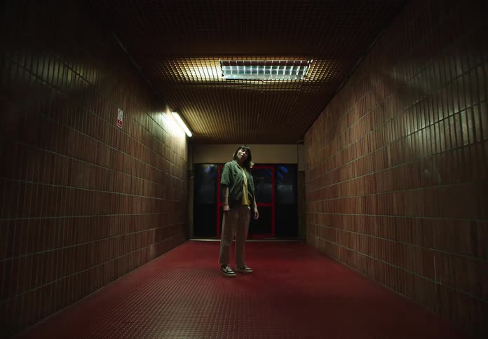 Woman standing in a nightlit hallway dancing moving arms and head