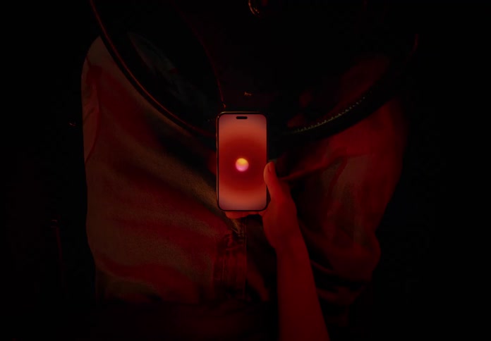 A person holds up an iphone smartphone watching a glowing ball