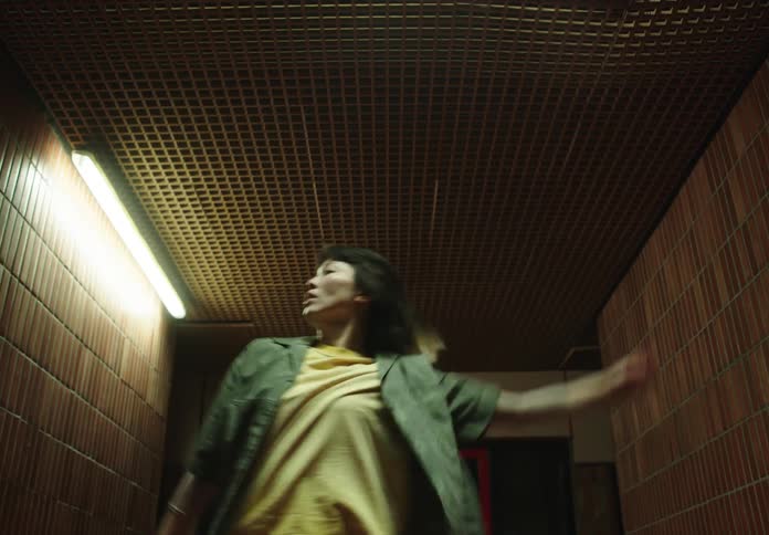 Woman in a lit hallway at night dancing