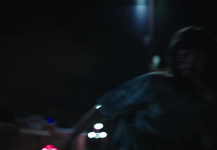 Female dancer with wavy hair and a blue t shirt dances on the street at night