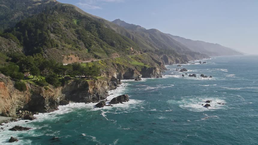 The waves crash against the rugged cliffs of a rocky coastline creating a dramatic scene