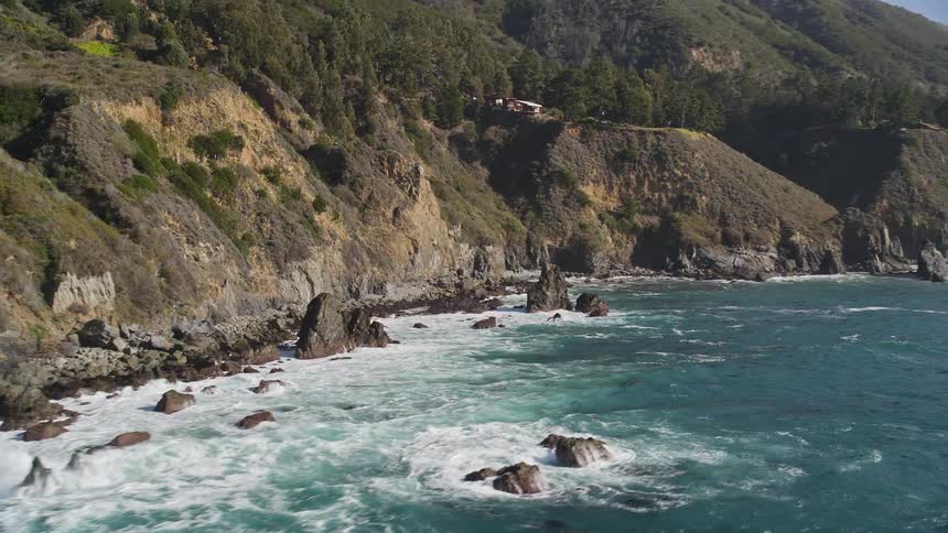 Aerial view of a rugged coastline with waves crashing against the shore