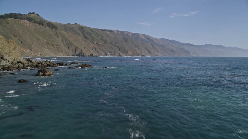 Aerial view of ocean waves crashing against a rocky coastline
