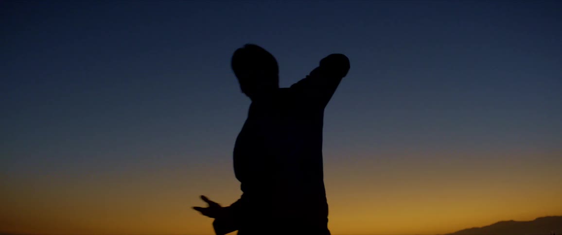 Silhouette of a person dancing against a red sky