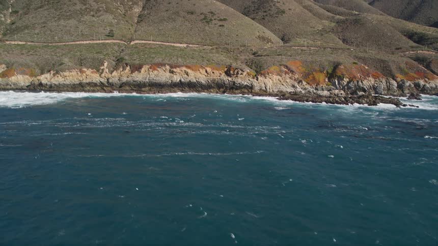 The powerful waves crash against the rocky shore of a remote mountain peak
