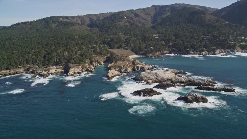 Aerial landscape of rocks in the middle of the sea and the wooded coast