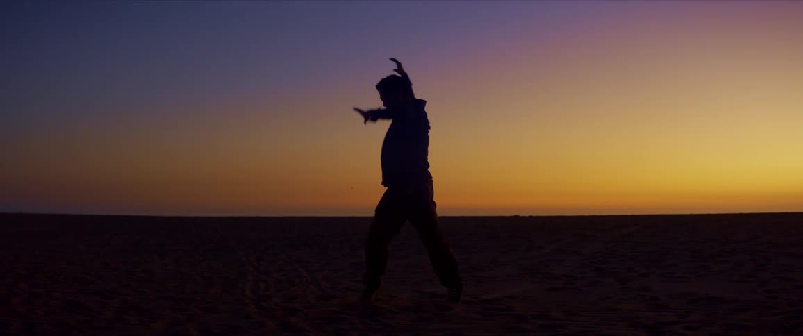 Silhouette of a person dancing on the beach on a red sky day