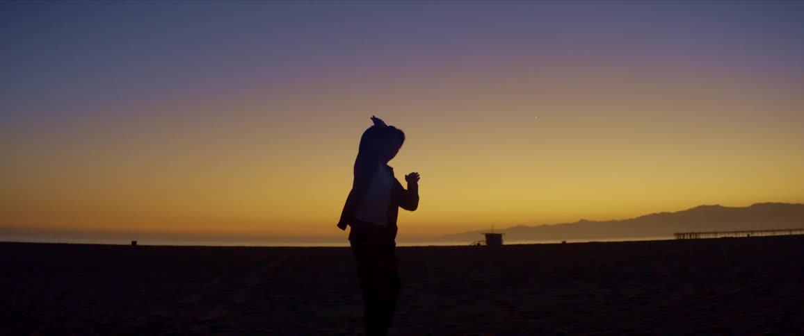 Dancer dancing on the beach sand in the late afternoon with a red sky