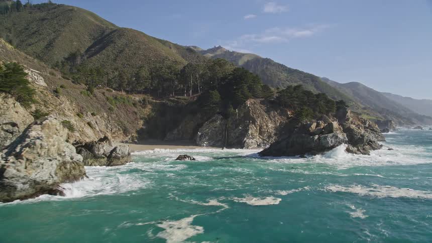 Vast ocean at the edge of a rocky shore with vegetation